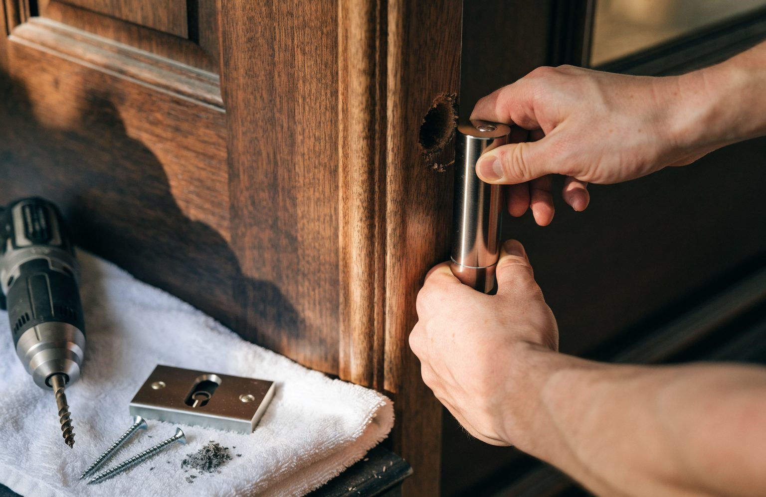 New deadbolt being fitted to a residential front door, with drill and strike plate ready