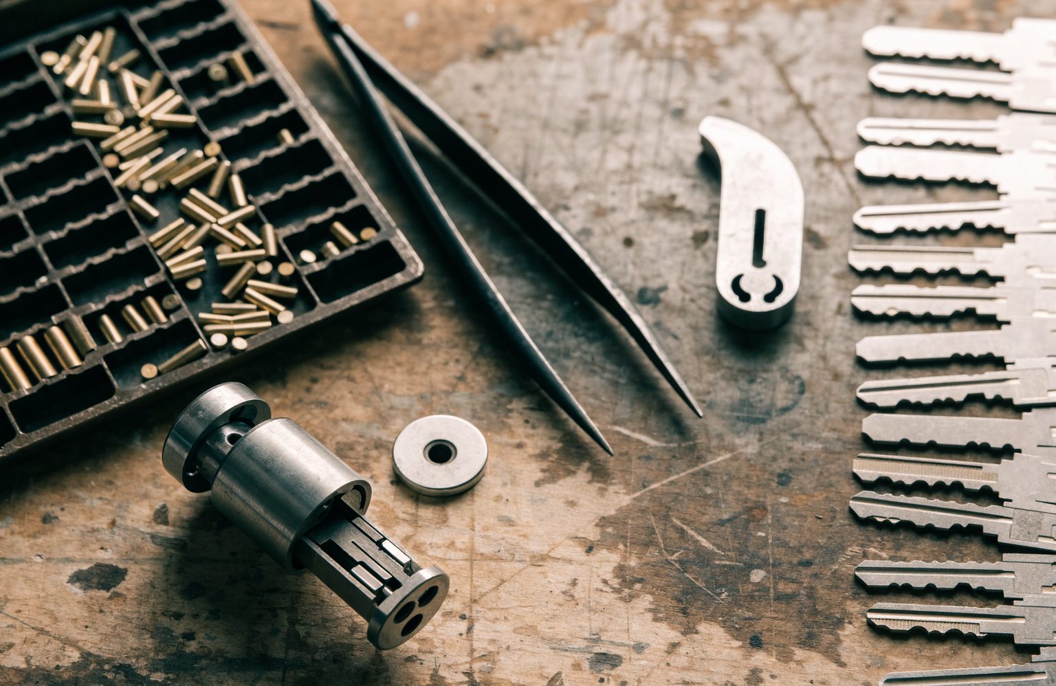 Locksmith bench set up for rekeying, with a stripped cylinder, pinning tray and key blanks