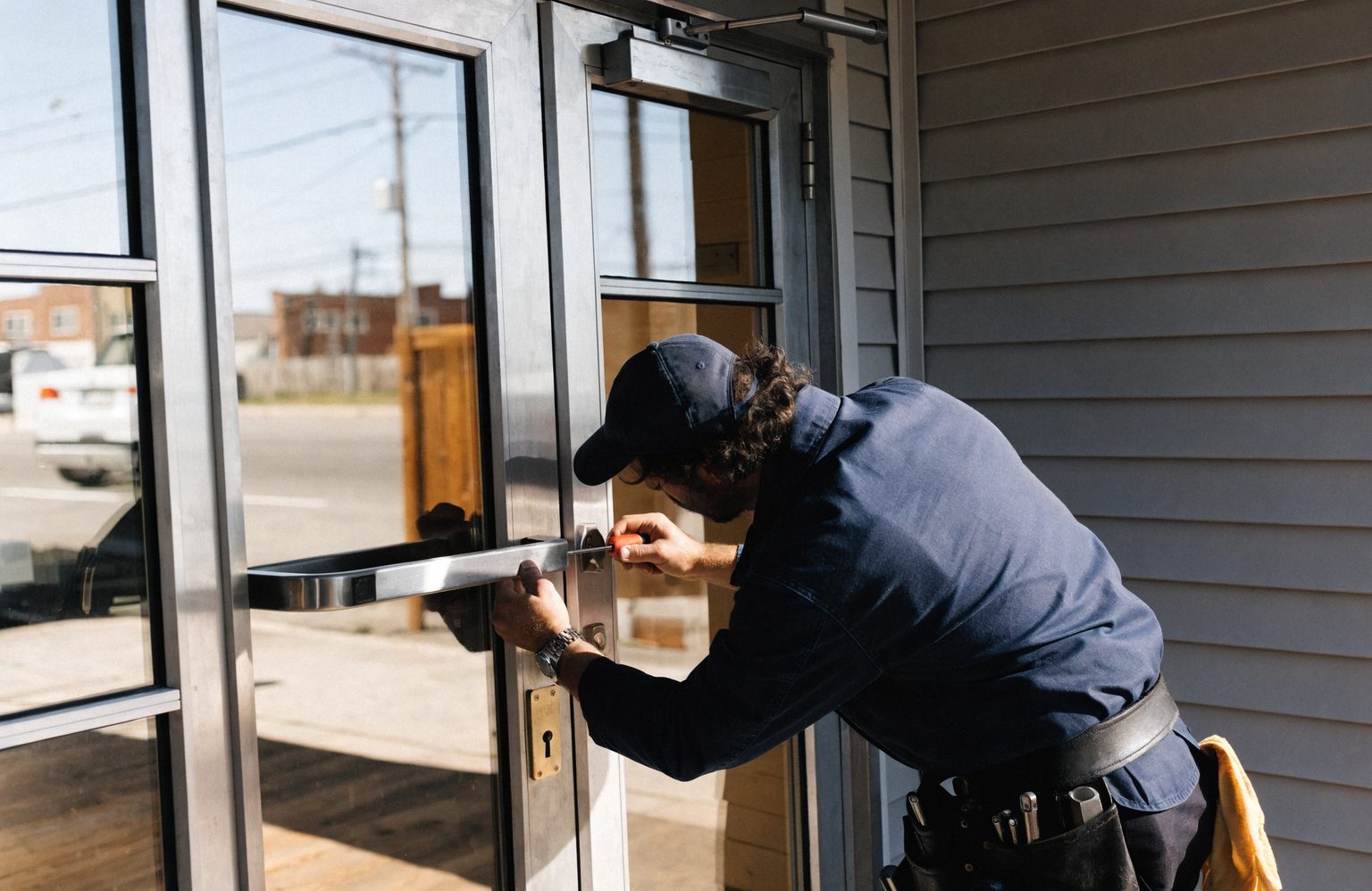 Locksmith servicing the push bar and lock on a commercial glass storefront door